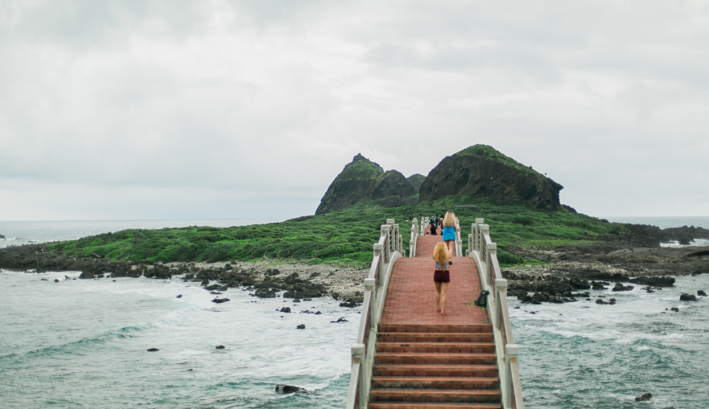 Students abroad in Taiwan cross a red bridge to a small island.