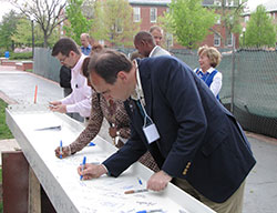 Board of trustees member David Otfinoski signs a steel beam to be used in the construction of the Johnson Center.