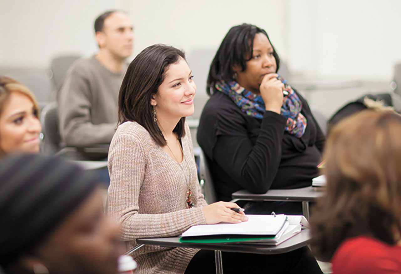 Adult students sit in the classroom attentive to the professor.