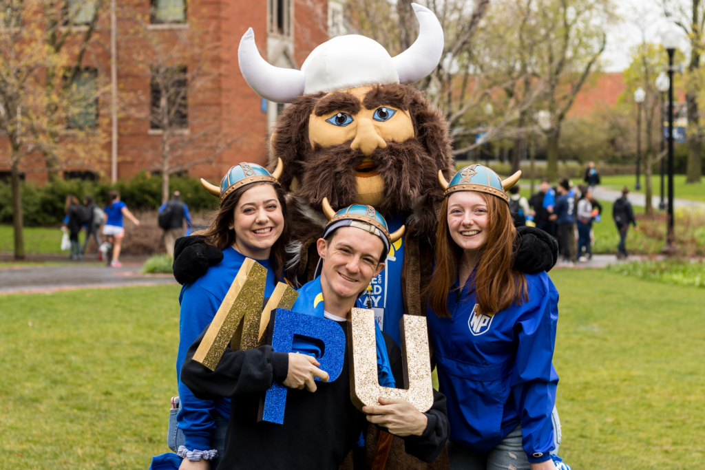 three students in blue and gold pose with Viking mascot