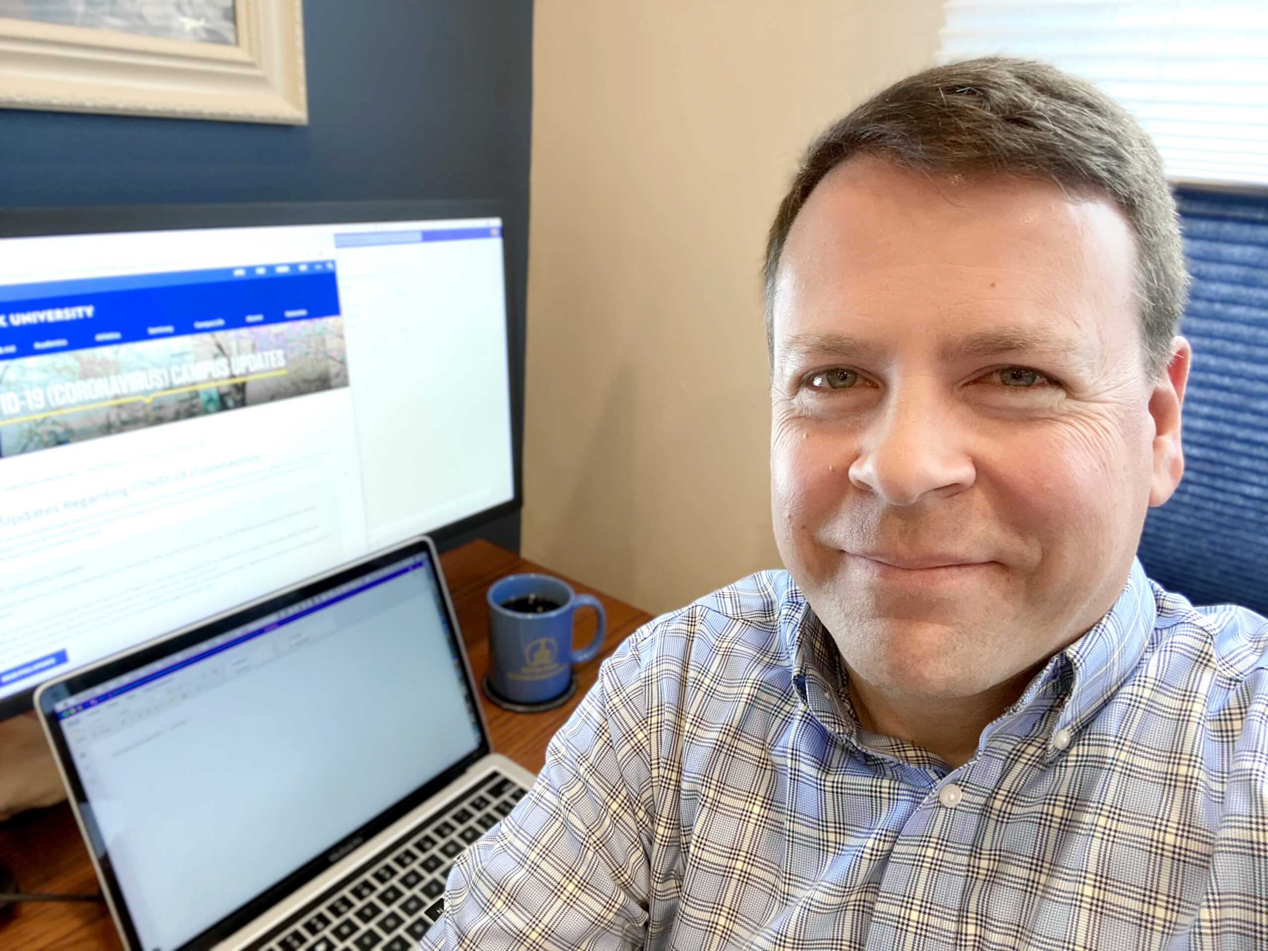 Man sits in front of computer at desk in home office.