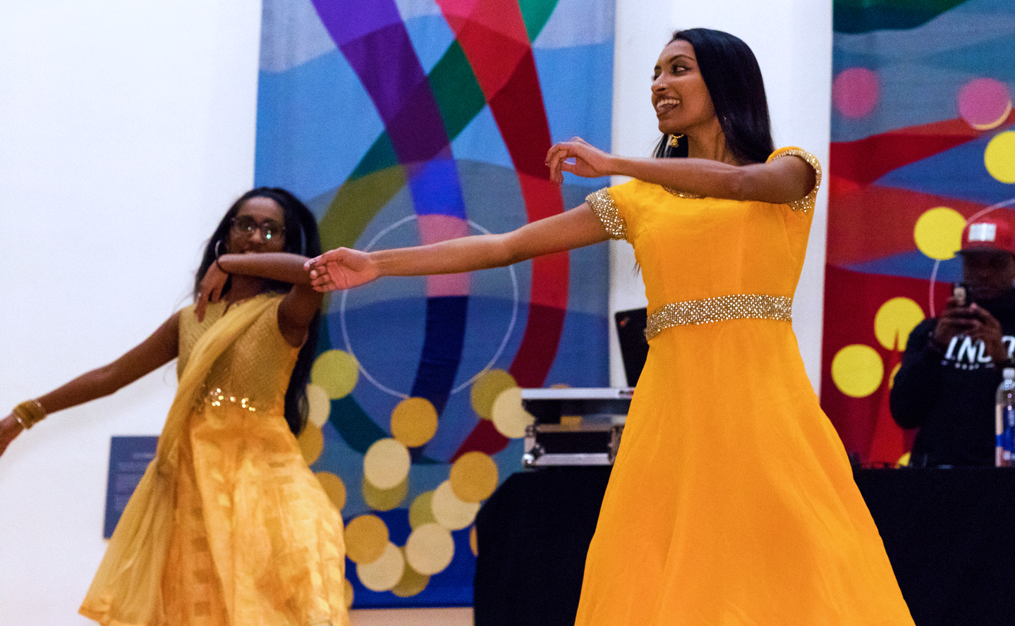 Two women in yellow dresses perform traditional dances at Diwali Festival.