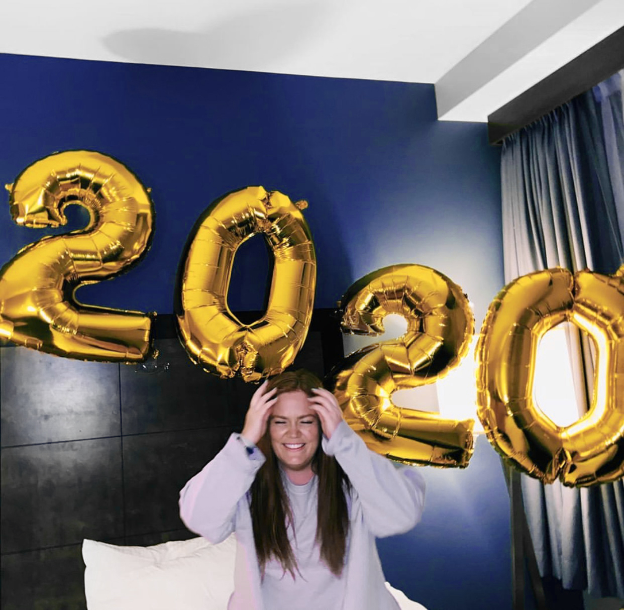 Female student celebrates graduation at home with 2020 balloon.
