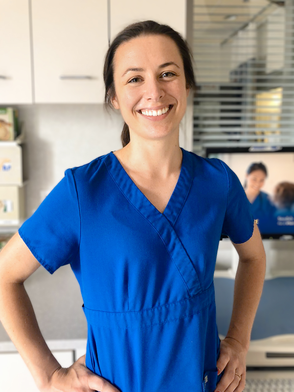 Woman wearing blue nursing scrubs in clinic.