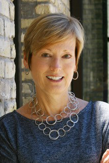 Smiling woman wearing blue top and silver hoop necklace