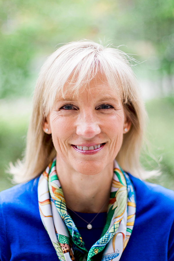 Smiling woman in blue top and colorful scarf.