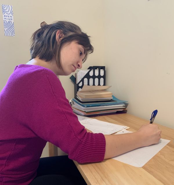 A ϲʿֱ Writing Center Writing Advisor (peer tutor) sits at a desk, composing a letter to her Letter Partner, an incarcerated student at the North Park Stateville Correctional Center Campus.