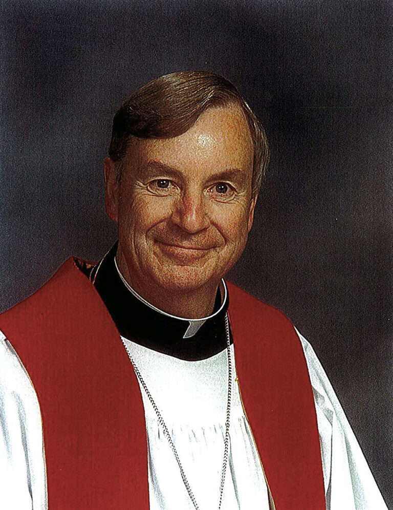 Man in minister's collar, white robe, and red stole