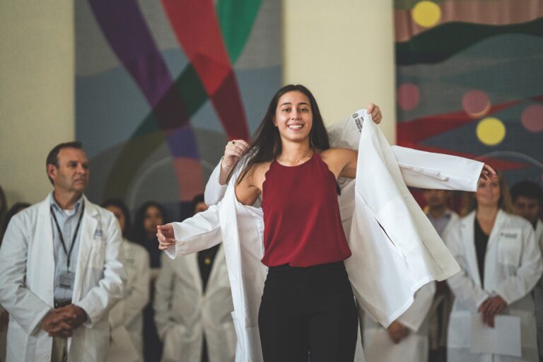 Nursing student putting on white coat at ceremony