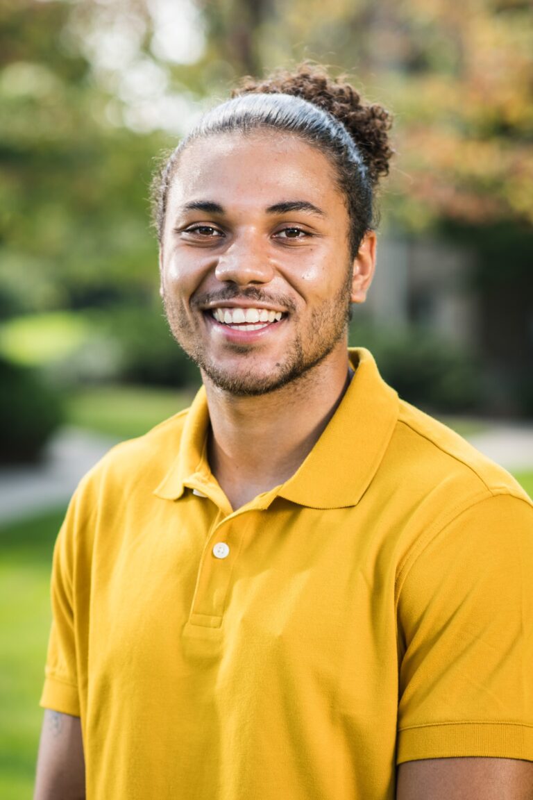 Photo of Sidney Francois-Friis as a student smiling in a yellow shirt.